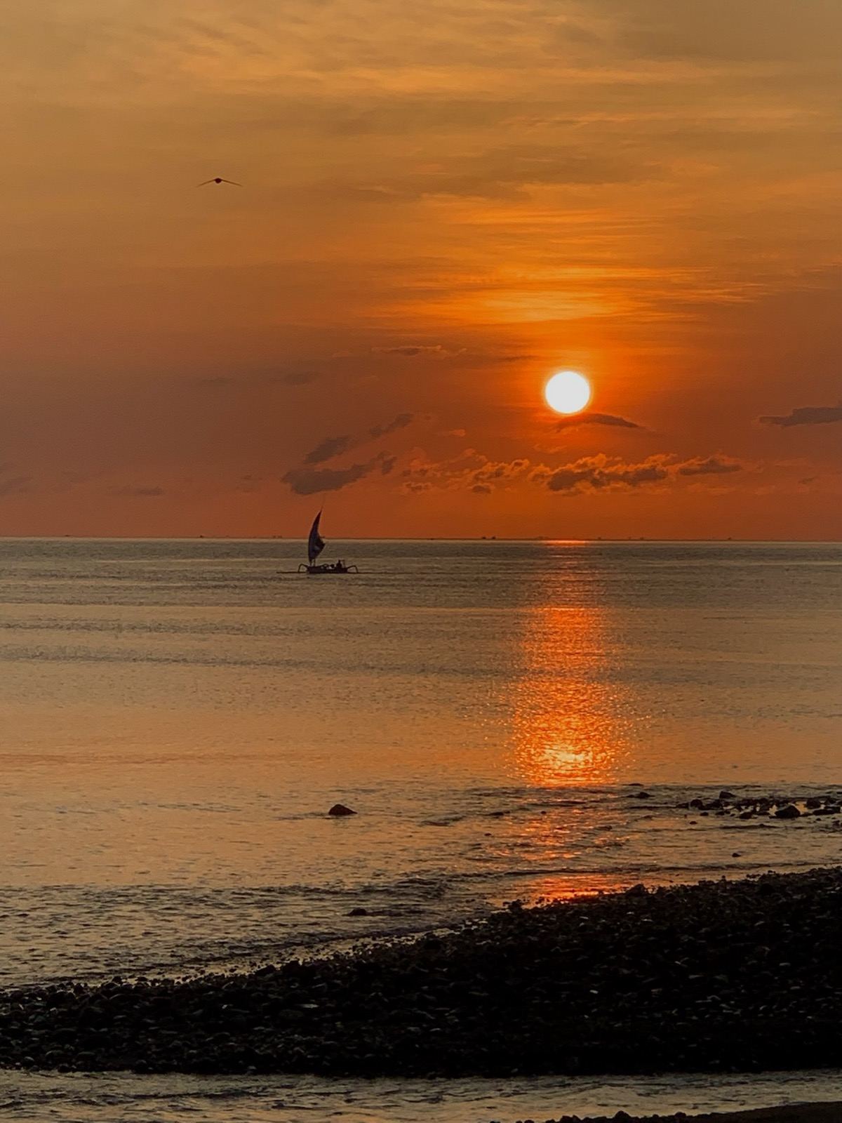 Sunset over the sea with a traditional jukung boat